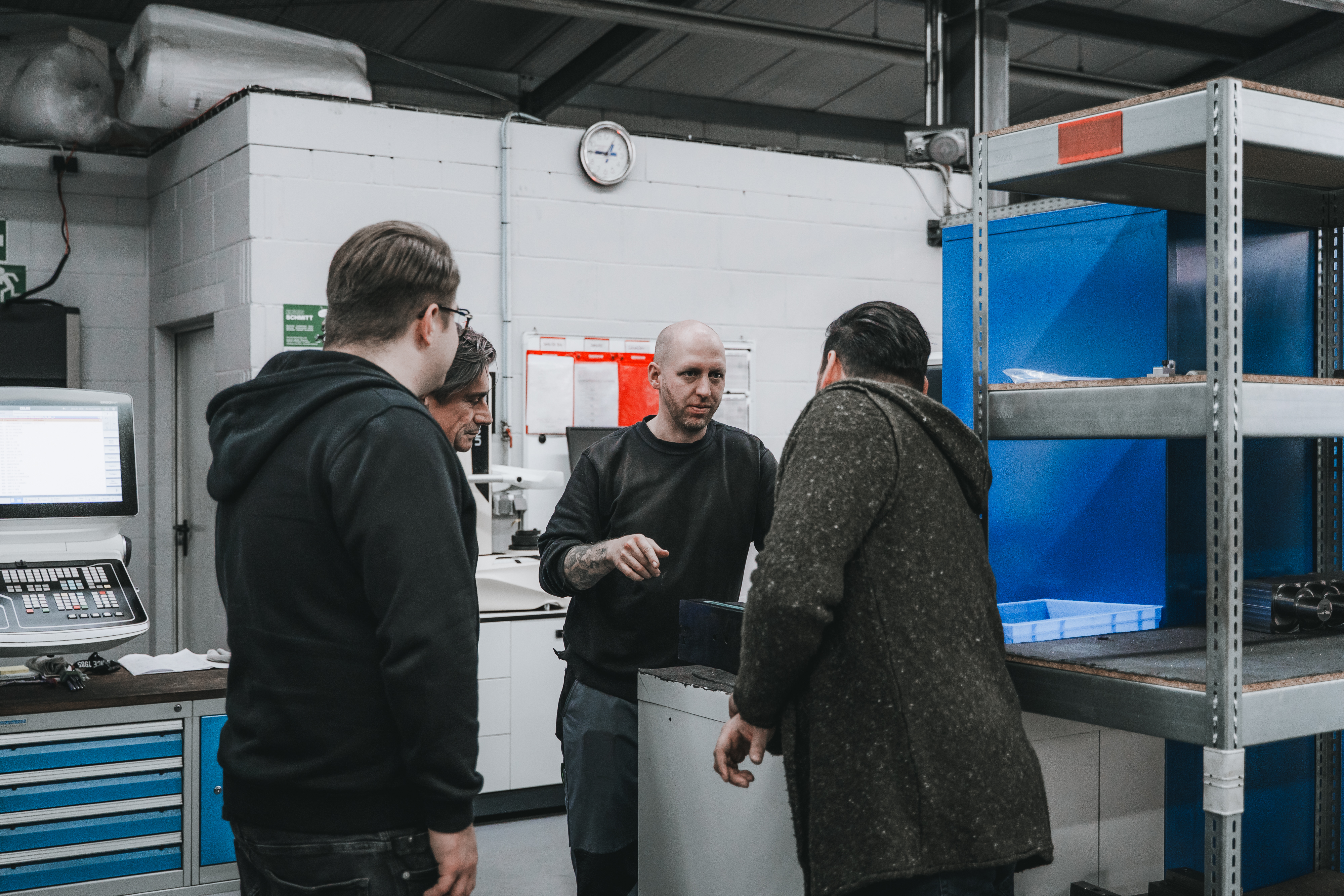 Gruppe von Personen die sich neben Maschinen unterhalten.