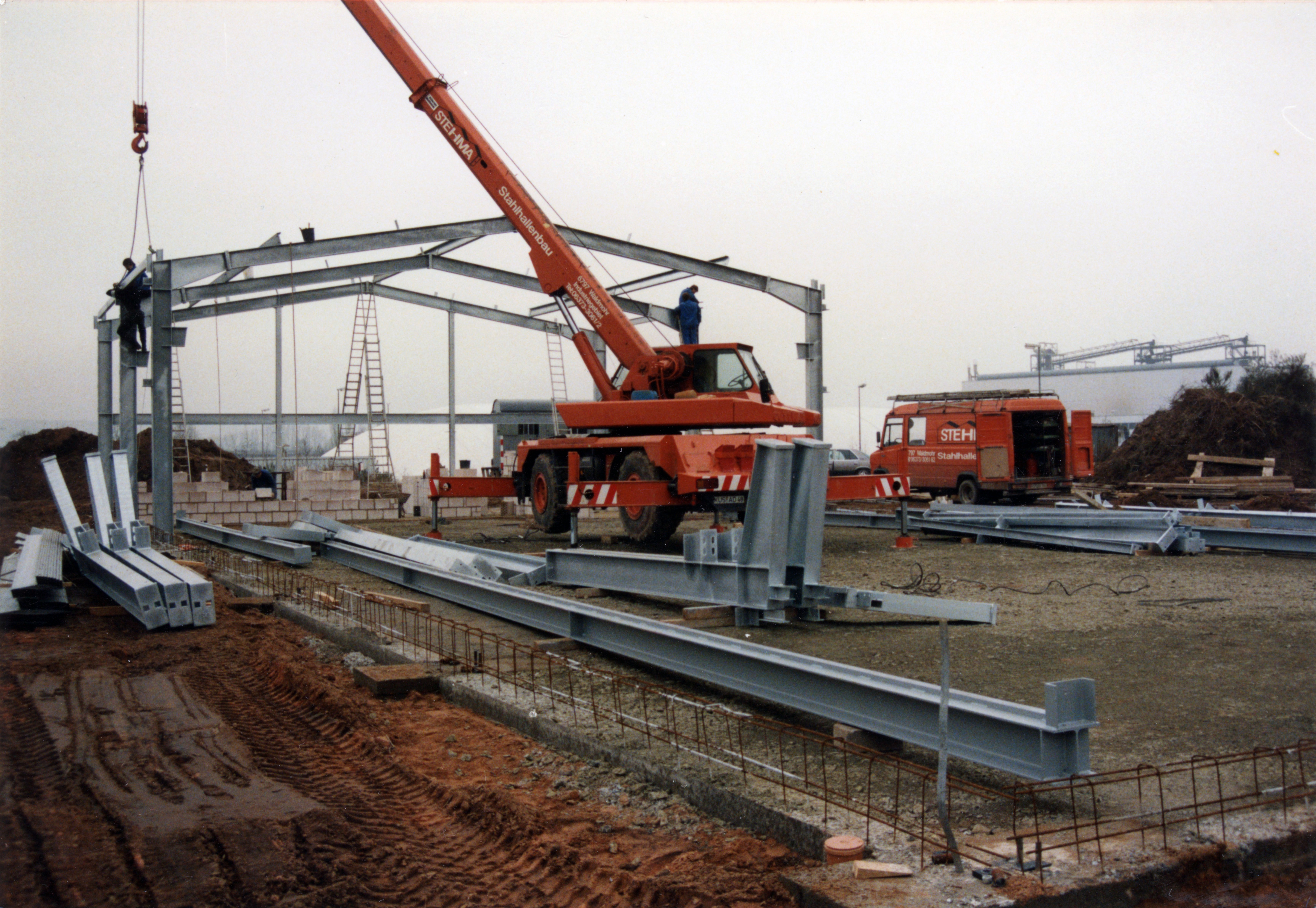 Lagerhalle in Konstruktion. Kran und Bewehrungsstahl sind zu sehen.