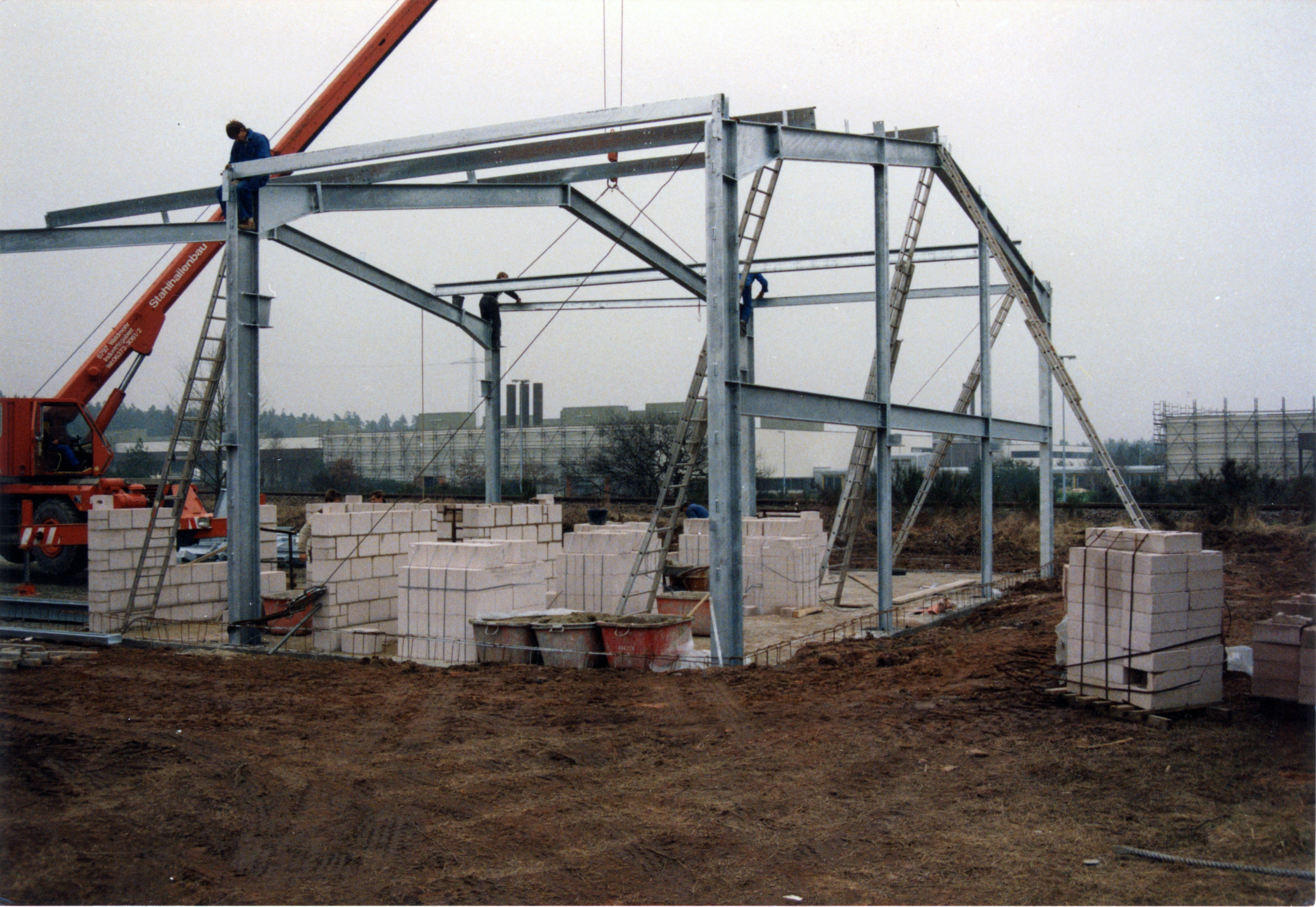 Lagerhalle in Konstruktion. Baumaterialien und Kran sind zu sehen.