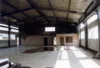 Leere Lagerhalle mit einer größeren Pfütze auf dem Boden.