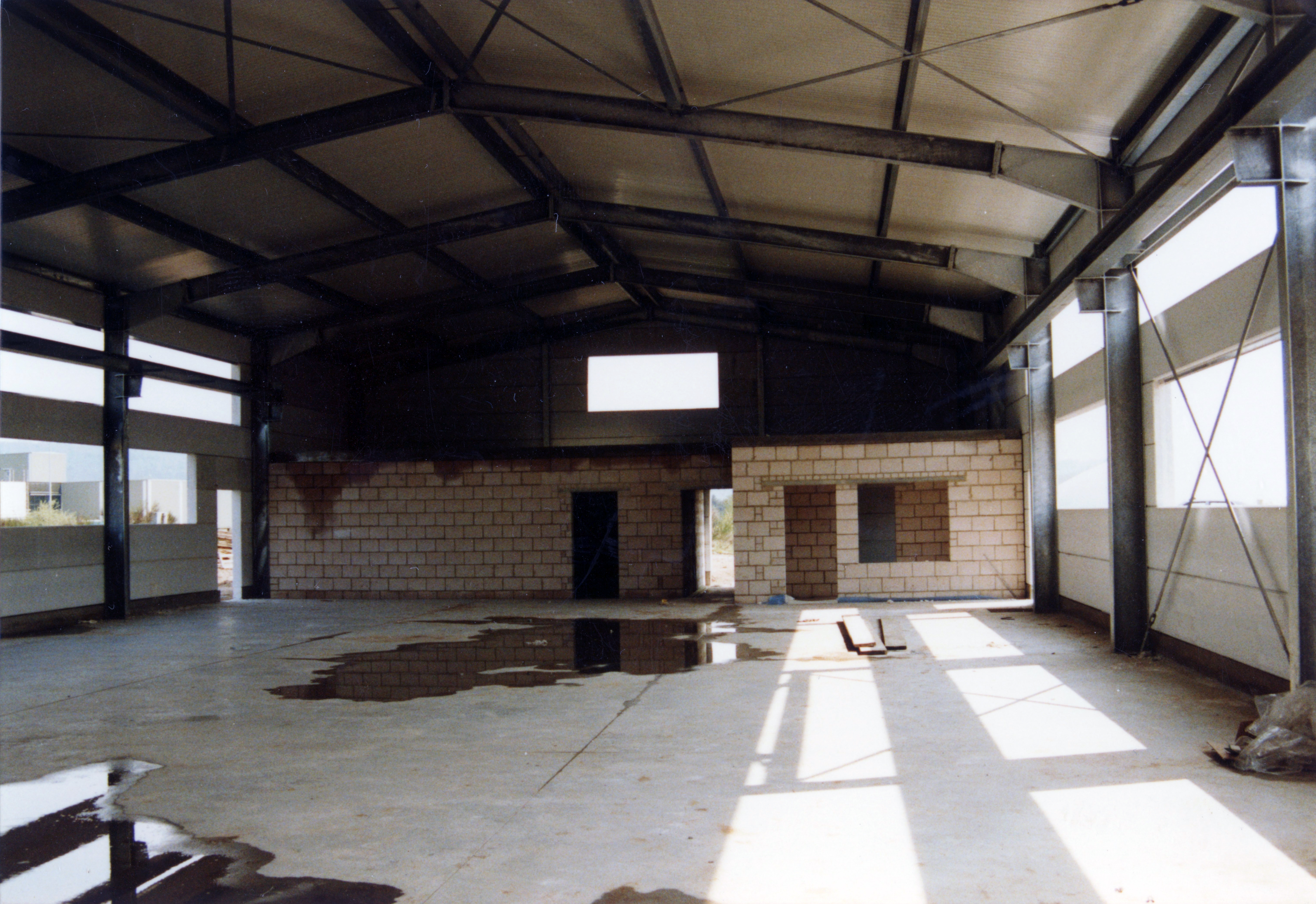 Leere Lagerhalle mit einer größeren Pfütze auf dem Boden.