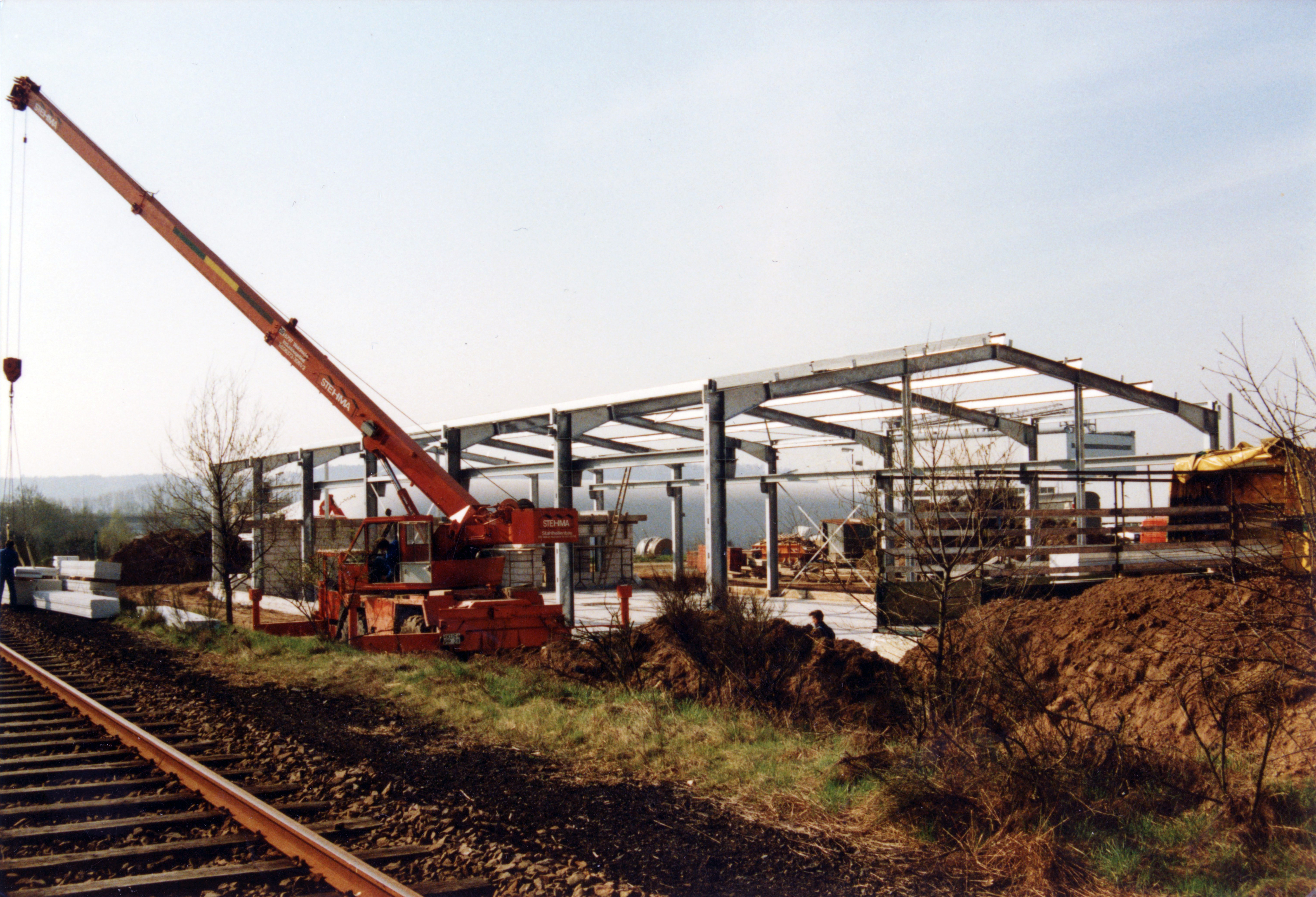 Lagerhalle in Konstruktion. Vorne dran verlaufen Schienen.