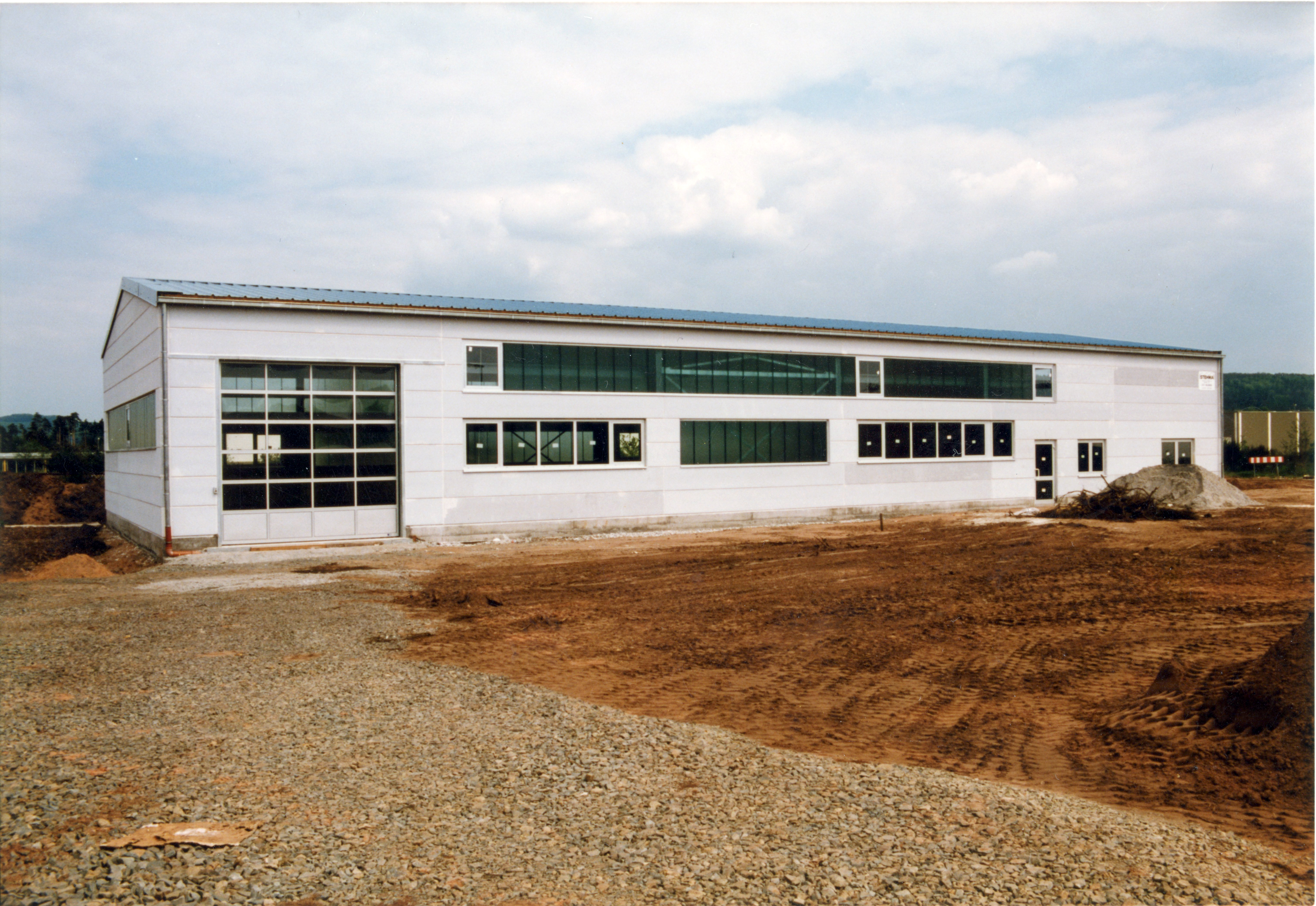 Lagerhalle von Außen mit einem großen Garagen artigem Eingang Links.